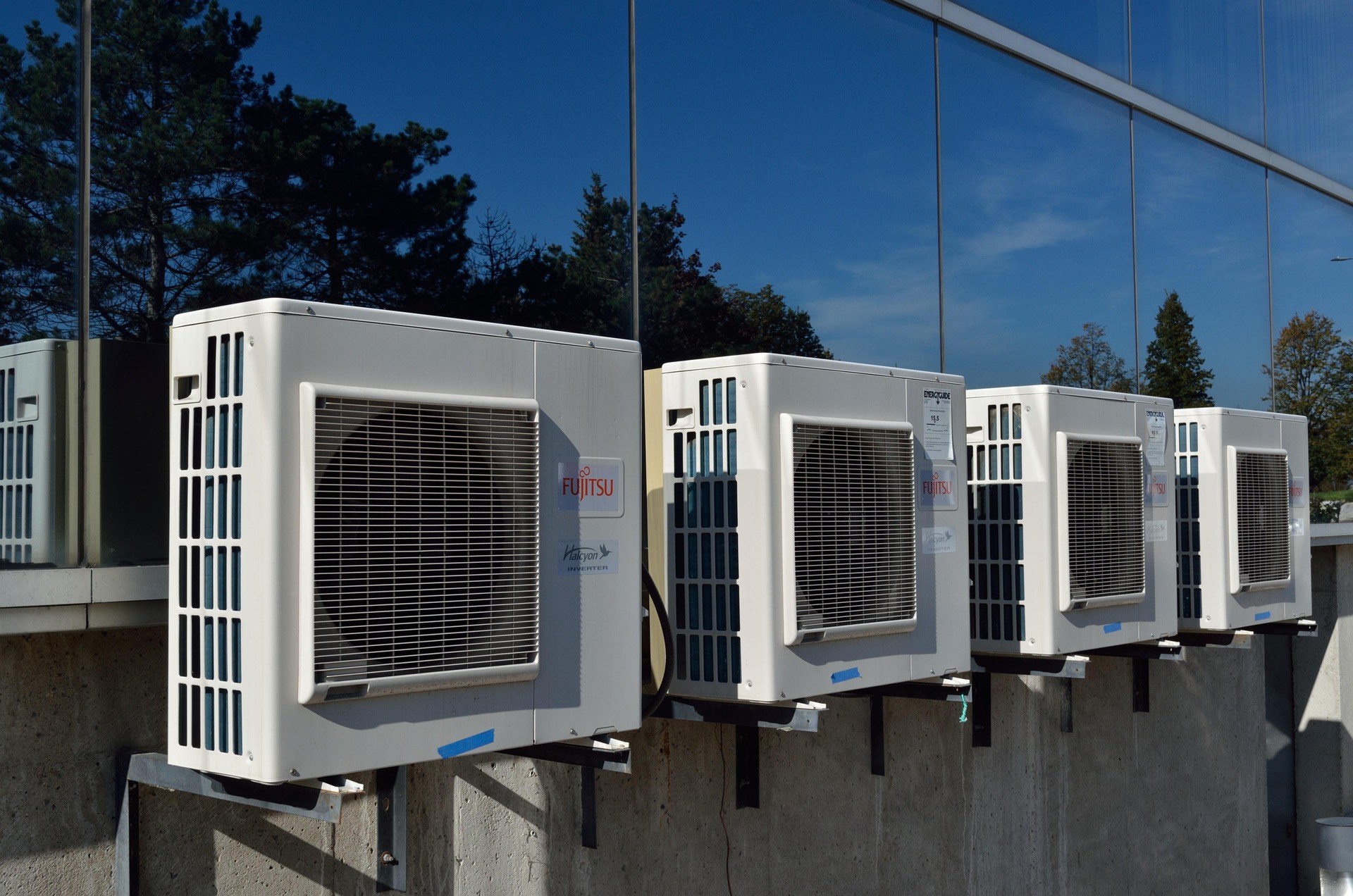 Row of outdoor air-conditioning condenser units on a commercial glass building