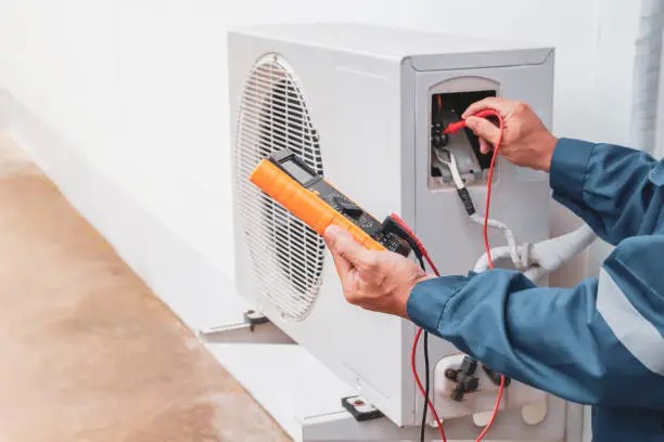 Technician using a multimeter to test an air-conditioning unit