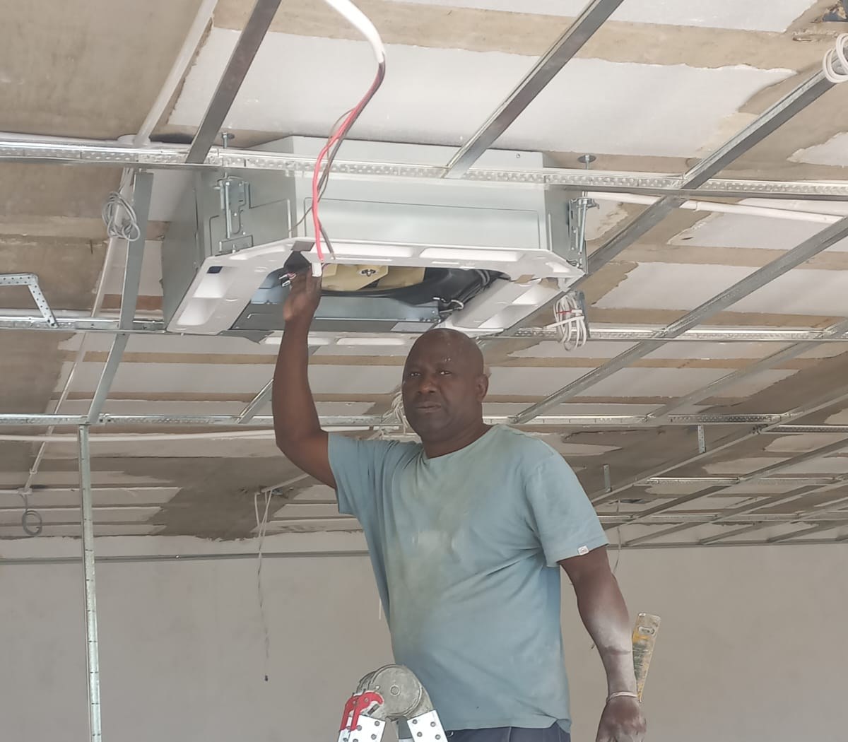 Easy Air technician servicing a ceiling-mounted air-conditioning unit on site